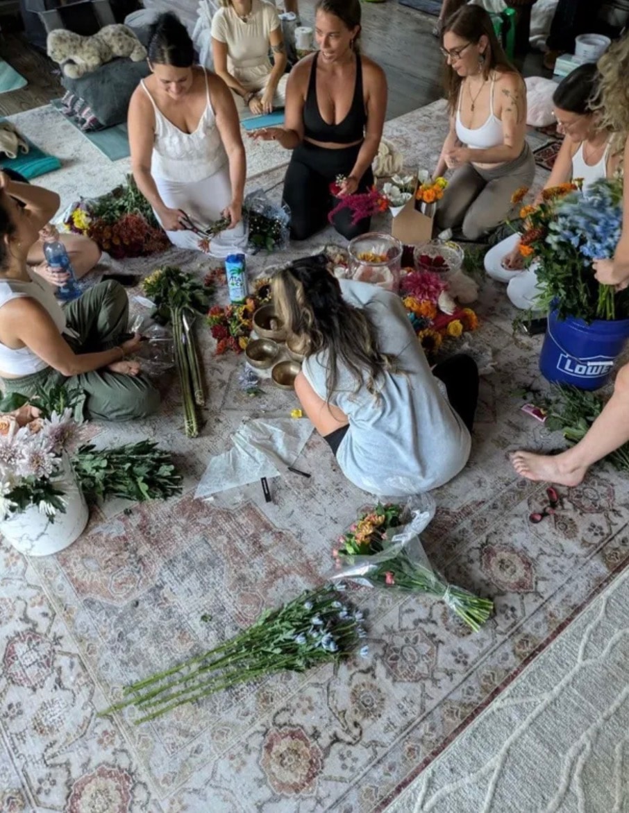 Group of women arranging flowers together in a circle during a healing gathering