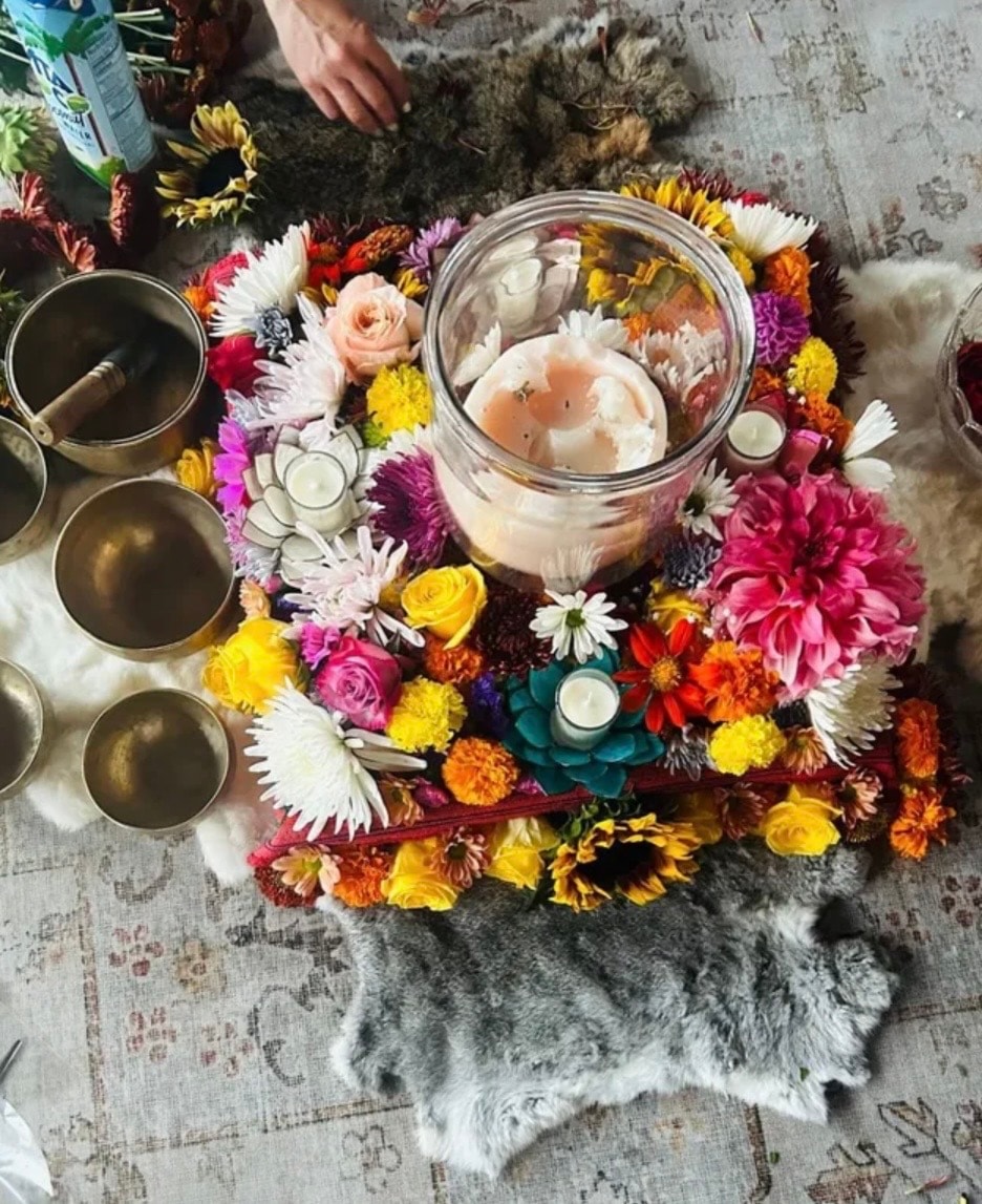Colorful floral altar with singing bowls, candles, and sacred offerings