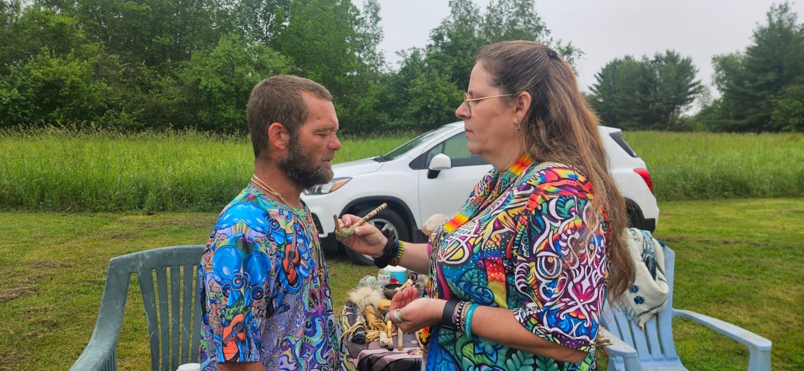 Angela administering Rapé ceremony to a participant outdoors in a field