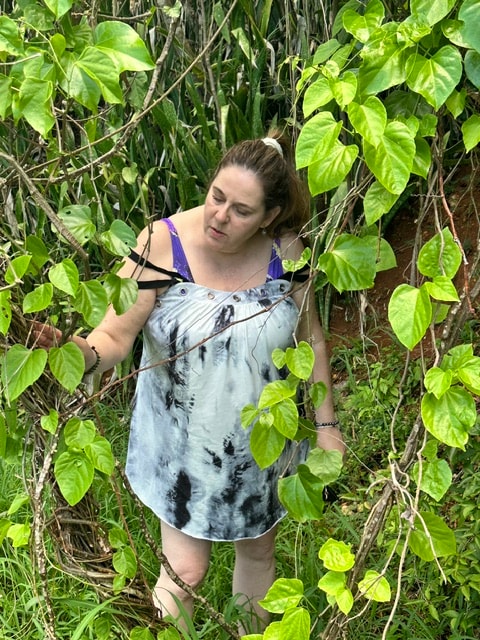 Angela standing among lush tropical vines and foliage