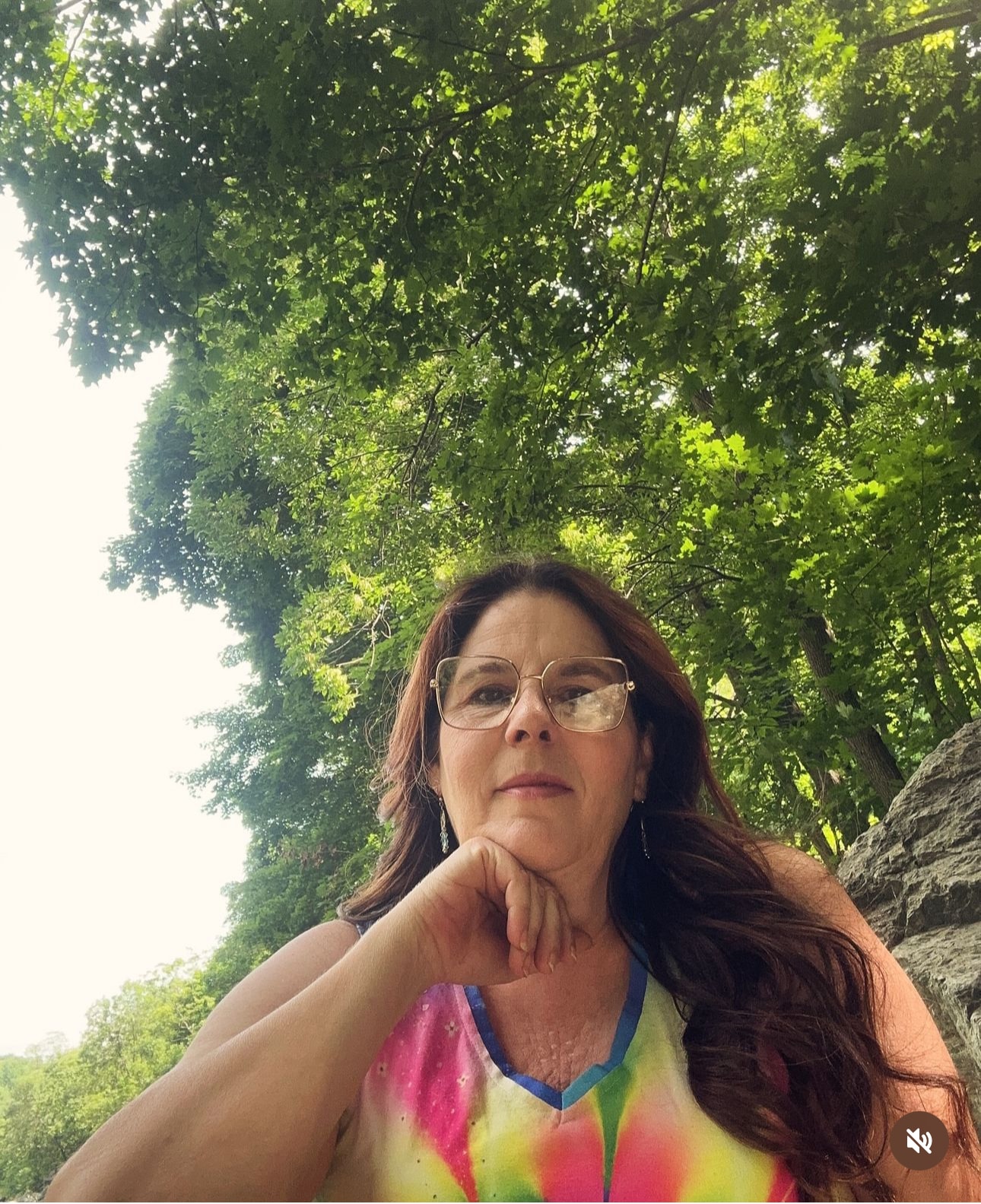 Angela posing under a tree canopy outdoors