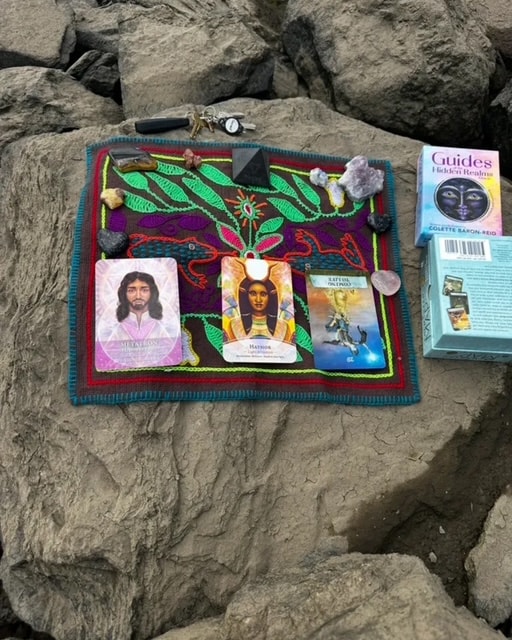 Sacred oracle card reading laid out on a colorful textile on the rocks