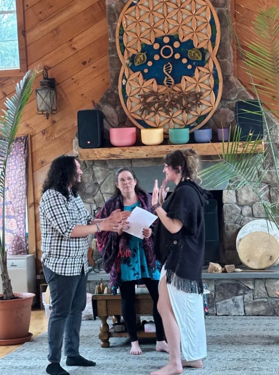 Angela officiating a ceremony in a beautiful rustic sacred space with a Flower of Life mandala