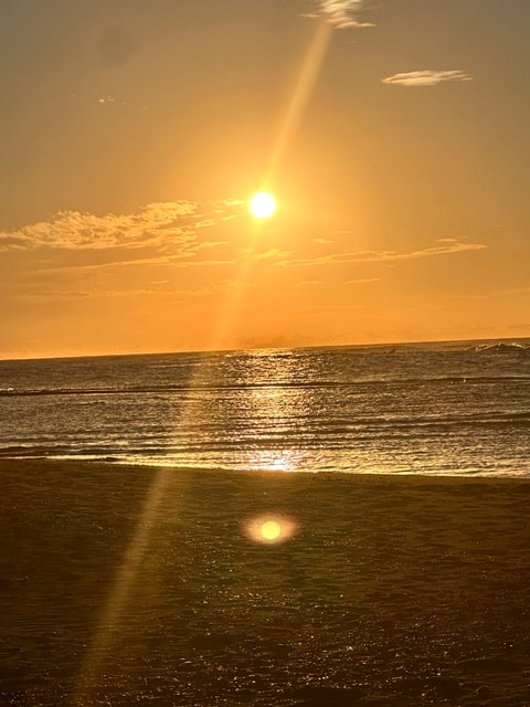 Golden sunrise over the ocean with light reflecting on the beach