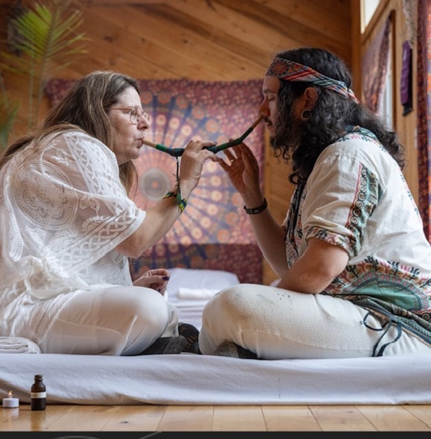 Two people sharing a sacred Rapé ceremony indoors in a ceremonial space