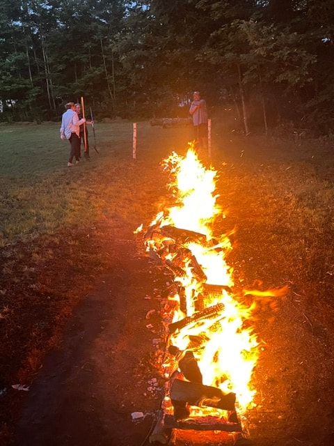 Firewalk ceremony with a long bed of flames and participants standing nearby