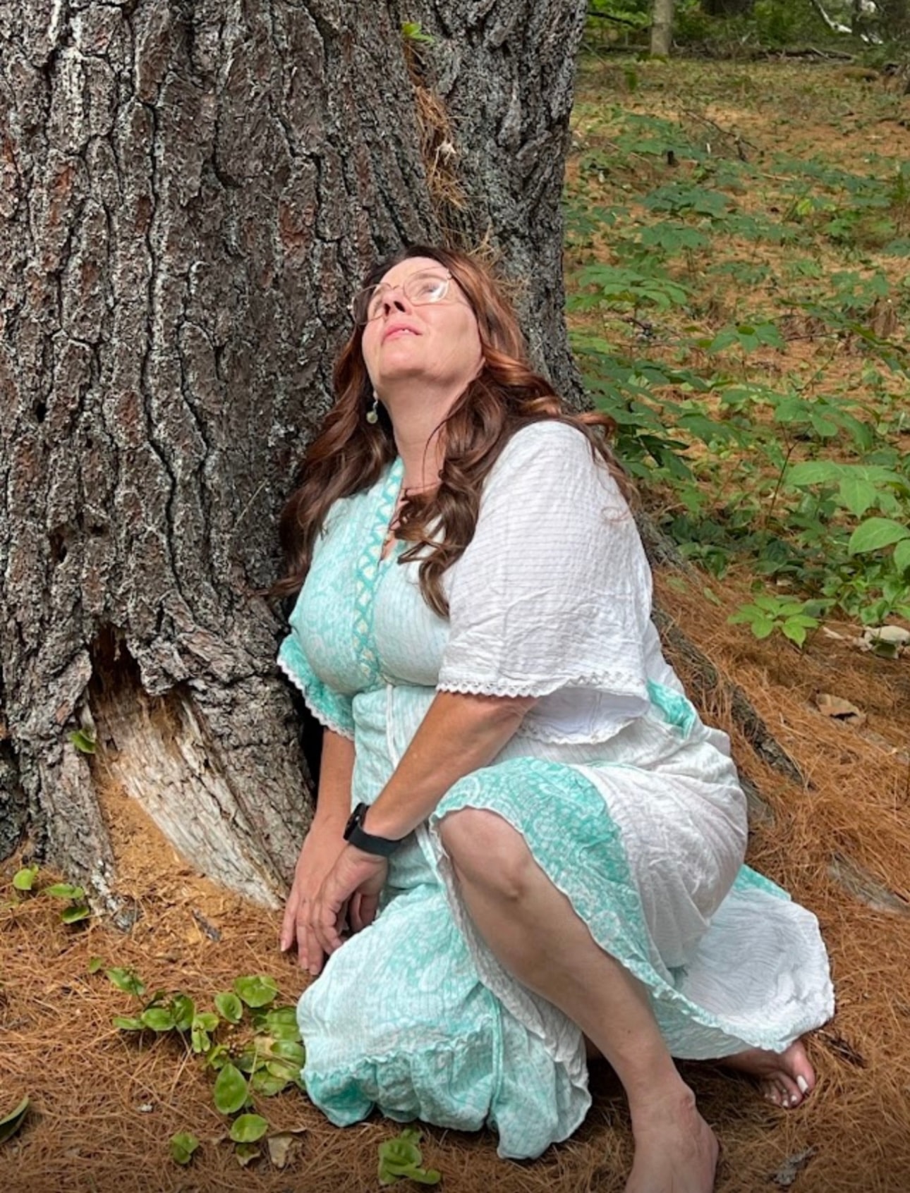 Angela kneeling against a large tree trunk